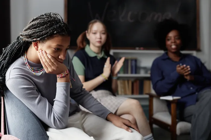 sad girl in classroom while others clap
